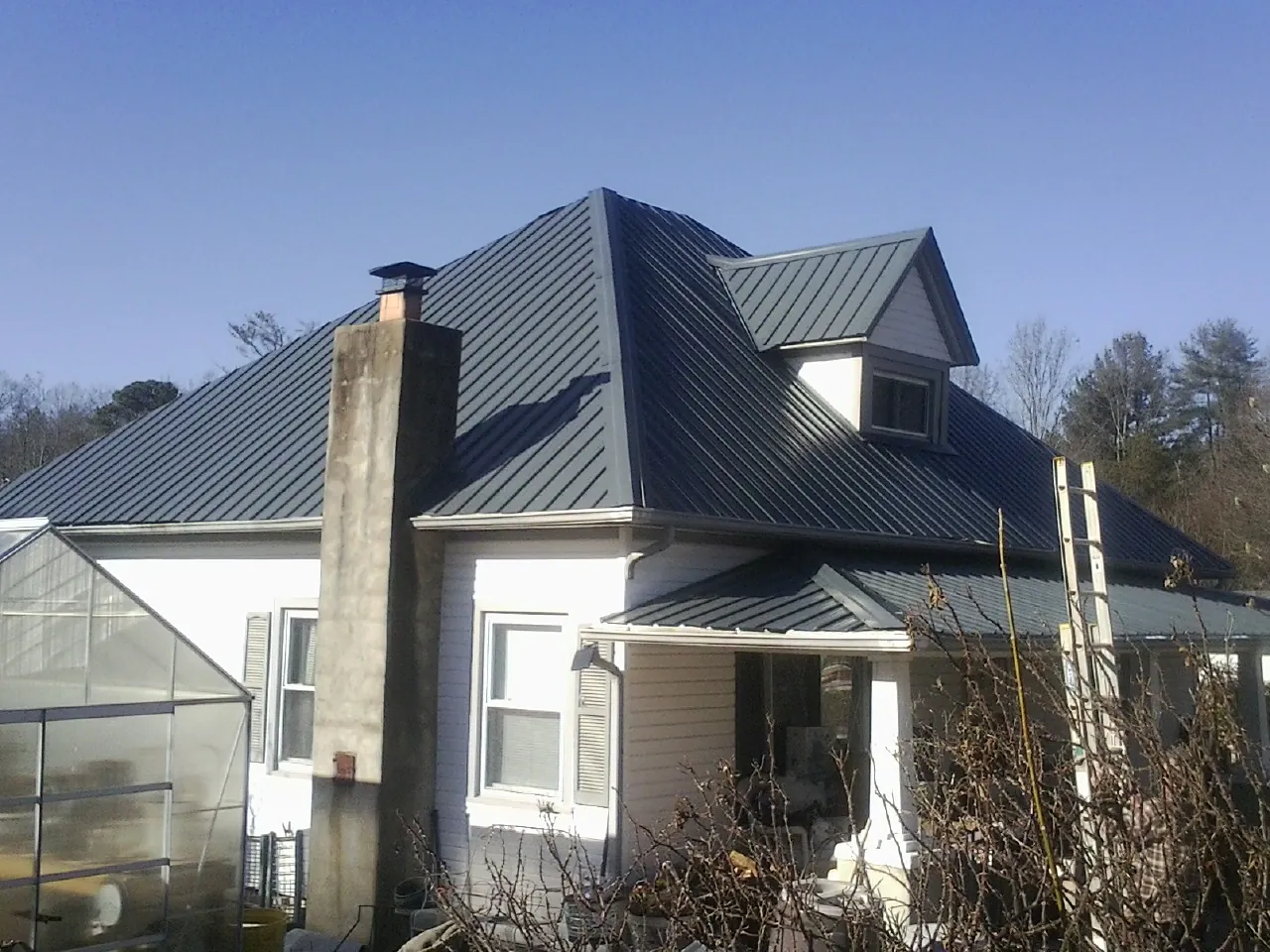 Dark blue standing seam metal roof on a white farmhouse with dormer — Slate & Tile Roof Repair by Roofing Brothers in Gambier