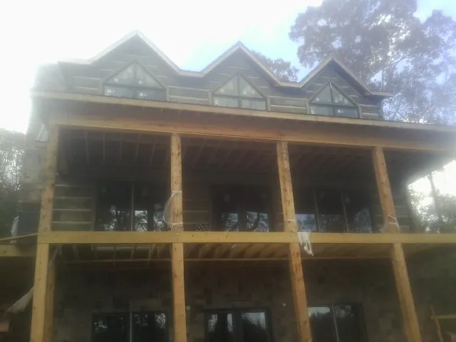 Dormers and porch framing on a large log home under construction — Roof Coating work by our crew in Gambier