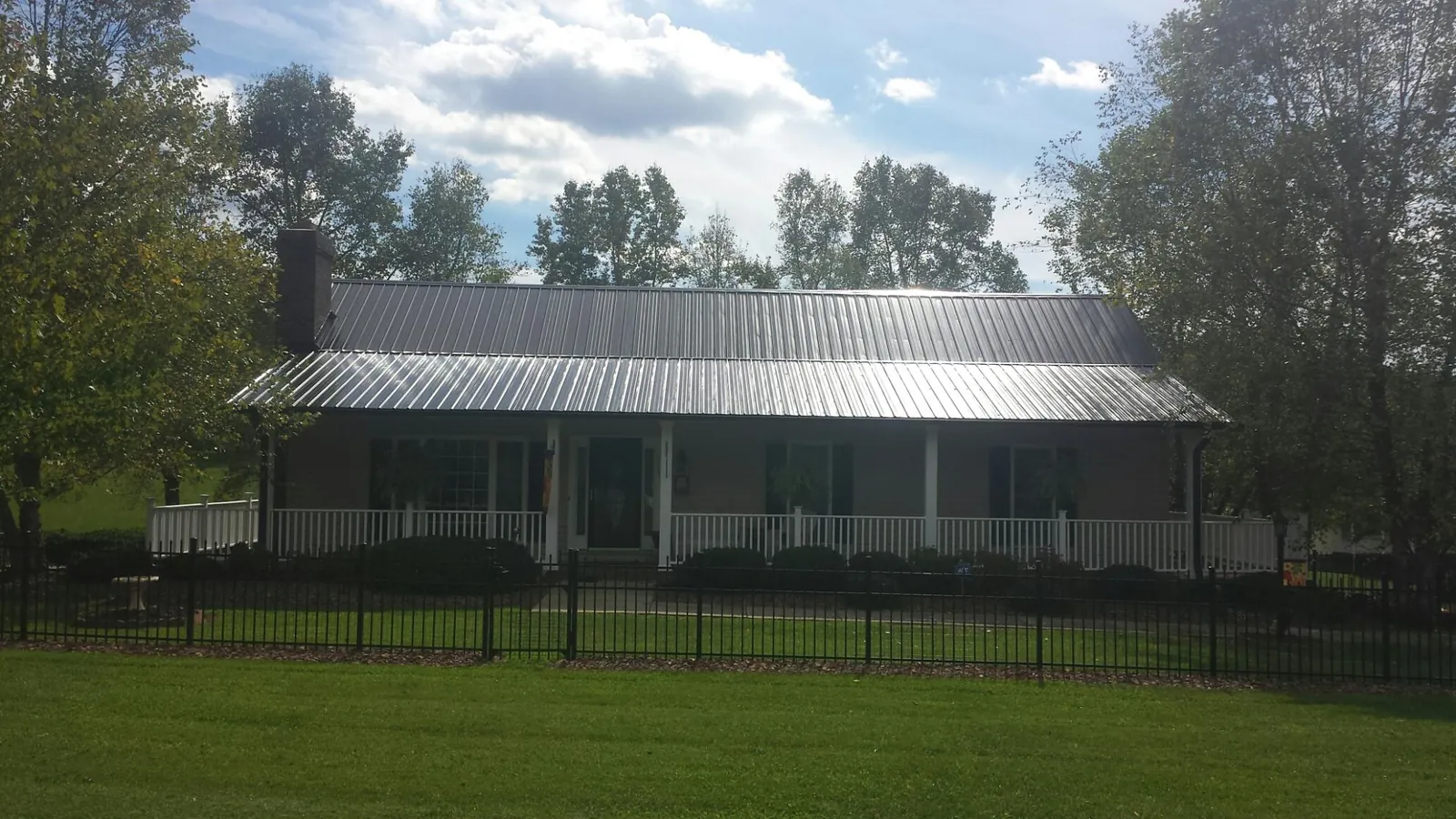 Gray metal roof on a brick ranch with a full width front porch — Gutter Guard Installation work by our crew in Gambier