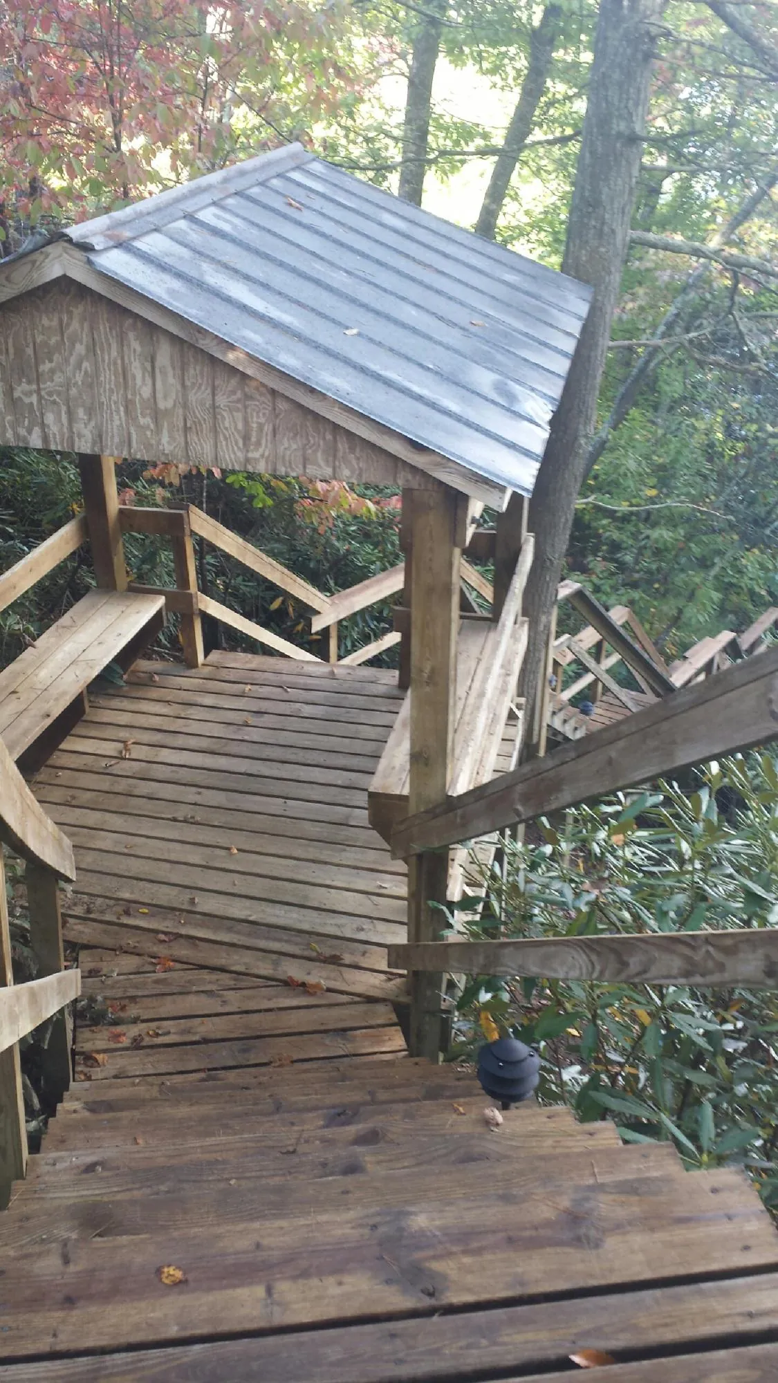 Metal roofed shelter over wooden steps on a wooded walkway — Skylight Repair & Installation work by our crew in Gambier