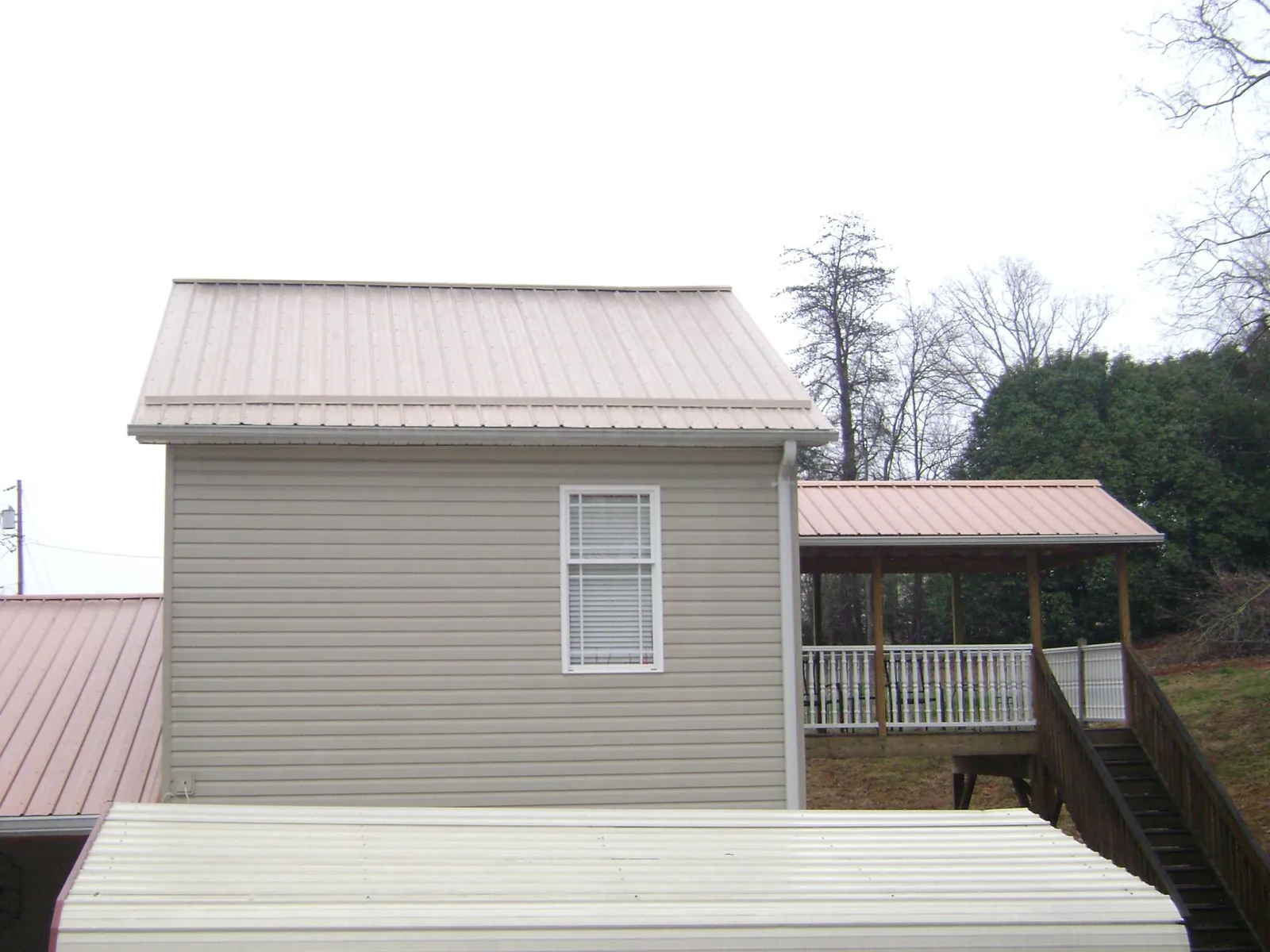 Tan metal roofs on a two story addition and attached porch, from a Roof Replacement job in Gambier
