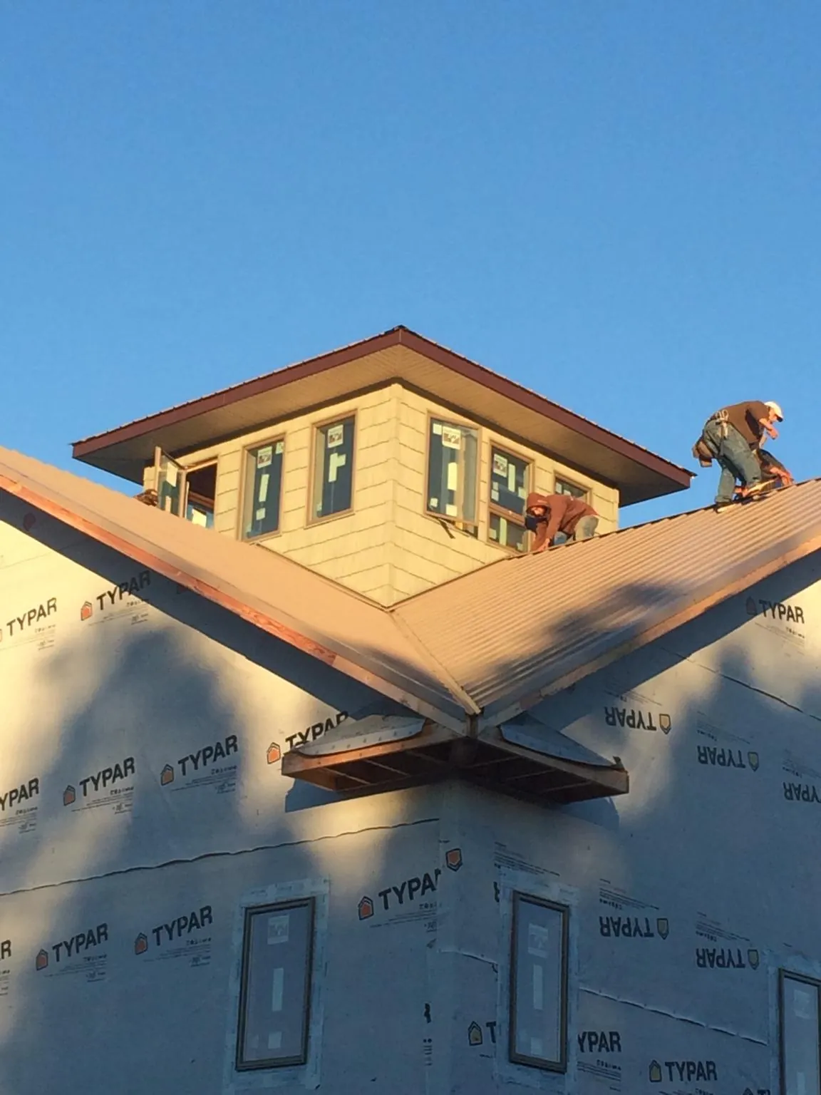 Roofers working around a rooftop cupola on a new metal roof at sunset — Roof Waterproofing in Gambier by Roofing Brothers